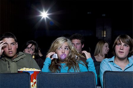 Girl talking on cell phone at movie theater with annoyed boy Stock Photo - Premium Royalty-Free, Code: 640-02773409