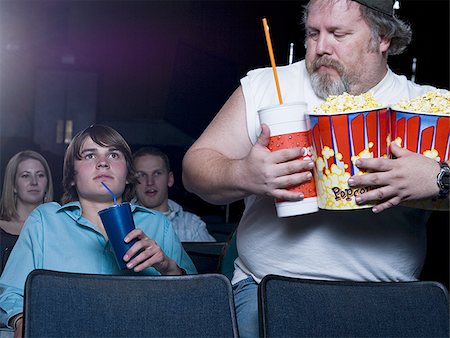 simsearch:640-02773406,k - Large man with buckets of popcorn and drink at movie theater Stock Photo - Premium Royalty-Free, Code: 640-02773414
