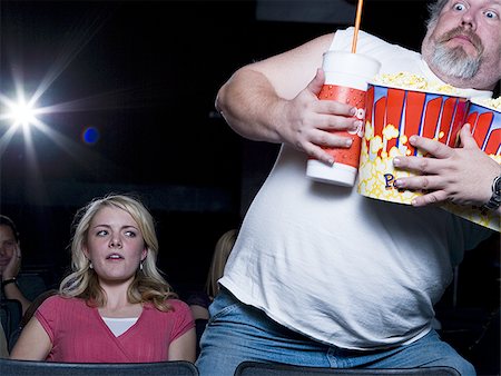 simsearch:640-02773406,k - Large man with buckets of popcorn and drink at movie theater Stock Photo - Premium Royalty-Free, Code: 640-02773415