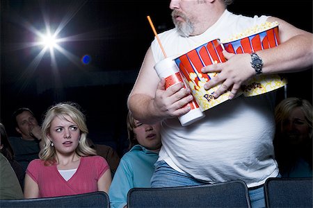 simsearch:640-02773406,k - Large man with buckets of popcorn and drink at movie theater Stock Photo - Premium Royalty-Free, Code: 640-02773417