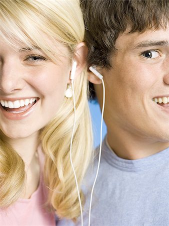 Portrait of a young couple with ear buds smiling Stock Photo - Premium Royalty-Free, Code: 640-02773489