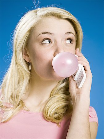 Girl talking on cell phone and blowing bubble Stock Photo - Premium Royalty-Free, Code: 640-02773520