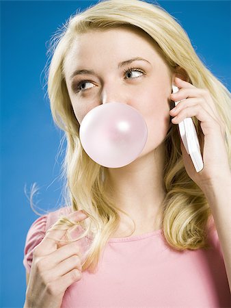 Girl talking on cell phone and blowing bubble Stock Photo - Premium Royalty-Free, Code: 640-02773521