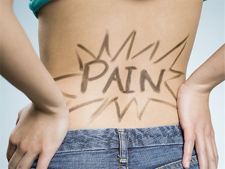 Rear view of woman with hands on lower back with Pain written on it Stock Photo - Premium Royalty-Free, Code: 640-02773733