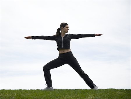 Side profile of woman stretching outdoors on grass Stock Photo - Premium Royalty-Free, Code: 640-02773854