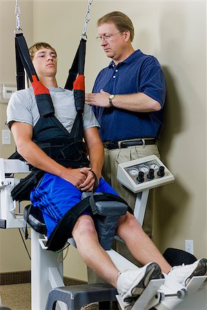 physiotherapist - young man in a suspension harness Stock Photo - Premium Royalty-Free, Code: 640-02949655