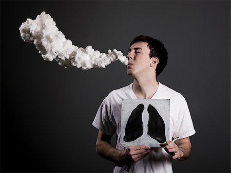 man with a lit cigarette holding up a drawing of black lungs in front of his chest Stock Photo - Premium Royalty-Free, Code: 640-02949997