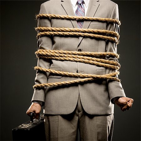 businessman in a full suit tied up with a rope around his mid section Stock Photo - Premium Royalty-Free, Code: 640-02952261