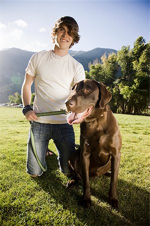 young man kneeling with a chocolate labrador retriever Stock Photo - Premium Royalty-Free, Code: 640-02952720