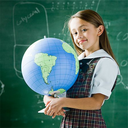 girl in a classroom standing in front of a chalkboard holding a globe Stock Photo - Premium Royalty-Free, Code: 640-02953482