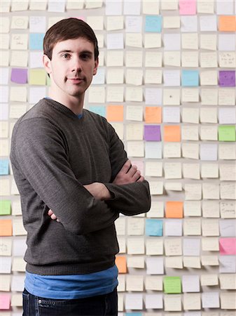 self adhesive note - Young man standing in front of wall covered with adhesive notes, portrait Stock Photo - Premium Royalty-Free, Code: 640-03256373
