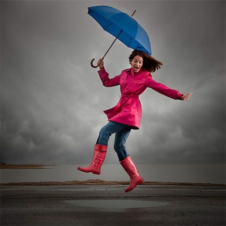 puddle in the rain - USA, Utah, Orem, woman with umbrella jumping under overcast sky Stock Photo - Premium Royalty-Free, Code: 640-03256961