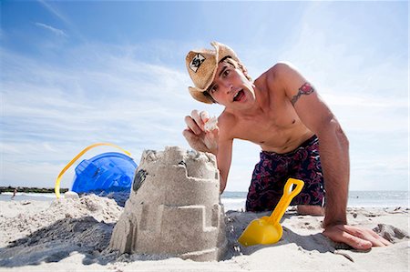 shovel (hand tool for digging) - Man building a sand castle at the beach Stock Photo - Premium Royalty-Free, Code: 640-03259244
