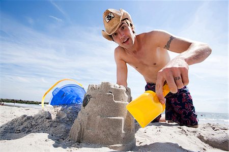shovel (hand tool for digging) - Man building a sand castle at the beach Stock Photo - Premium Royalty-Free, Code: 640-03259242