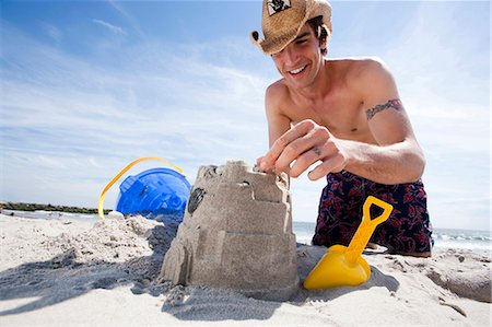 shovel (hand tool for digging) - Man building a sand castle at the beach Stock Photo - Premium Royalty-Free, Code: 640-03259243