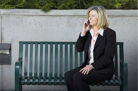 Businesswoman on cellular sitting on a bench Stock Photo - Premium Royalty-Free, Code: 640-03259479