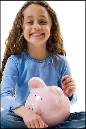 Young girl depositing money in piggy bank Stock Photo - Premium Royalty-Free, Code: 640-03265237