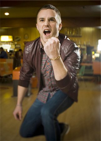 ecstatic - Young man with his arms raised in excitement in a bowling alley Stock Photo - Premium Royalty-Free, Code: 640-03265565