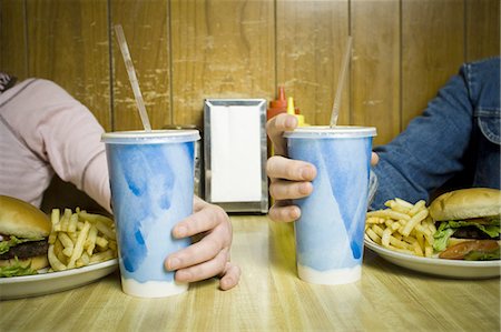 food and fast food - Close-up of a teenage girl and young man seated at the table in a restaurant Stock Photo - Premium Royalty-Free, Code: 640-03265626