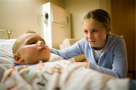 Young girl sitting by brother in hospital bed Stock Photo - Premium Royalty-Free, Code: 640-03261657