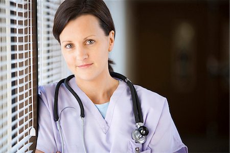 Female nurse leaning on blinds Stock Photo - Premium Royalty-Free, Code: 640-03261684