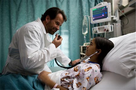 Doctor examining girl in hospital bed Stock Photo - Premium Royalty-Free, Code: 640-03261839