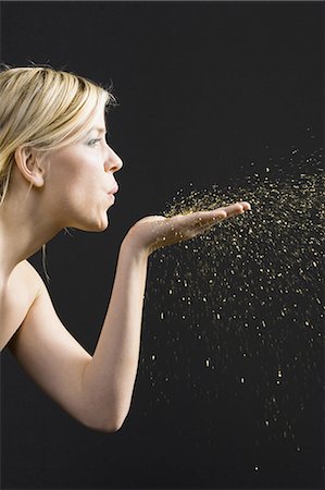 Profile of woman blowing gold dust from hand Stock Photo - Premium Royalty-Free, Code: 640-03262407