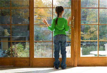 Young girl looking through large window Stock Photo - Premium Royalty-Free, Code: 640-03262727