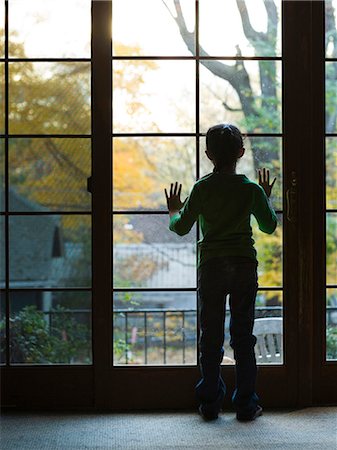Young girl looking through large window Stock Photo - Premium Royalty-Free, Code: 640-03262729