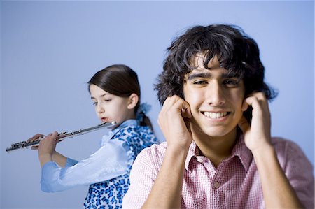 Girl playing the flute with her brother not listening Stock Photo - Premium Royalty-Free, Code: 640-03263409