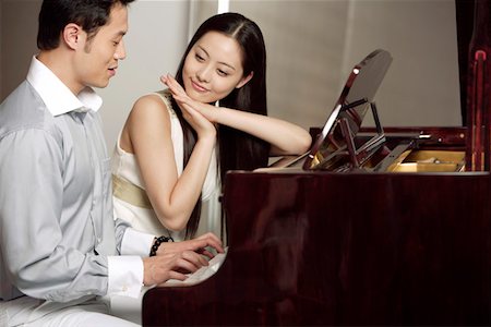 piano performance dress - Young couple playing grand piano, smiling Foto de stock - Sin royalties Premium, Código: 642-01734446