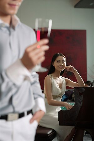 piano performance dress - Woman playing piano with man holding wineglass in the foreground Foto de stock - Sin royalties Premium, Código: 642-01734455