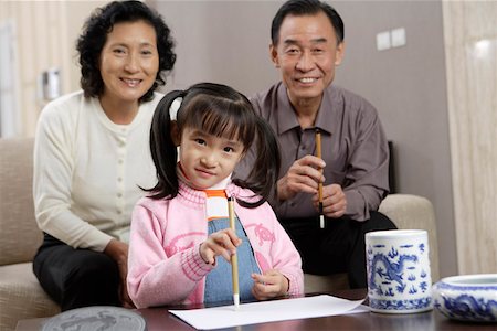 Senior couple with grandson holding painting brush and smiling Stock Photo - Premium Royalty-Free, Code: 642-01735341