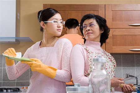 simsearch:6108-06167085,k - Women wearing apron looking at each other while man standing in background Stock Photo - Premium Royalty-Free, Code: 642-01736652