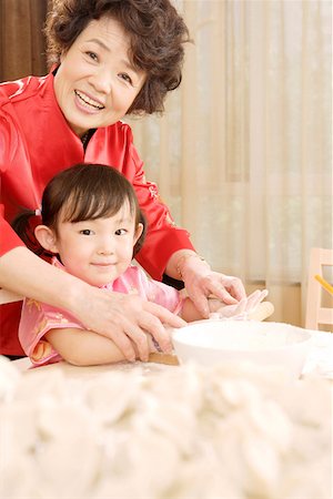 Grandmother teaching granddaughter making dumplings Stock Photo - Premium Royalty-Free, Code: 642-01736961