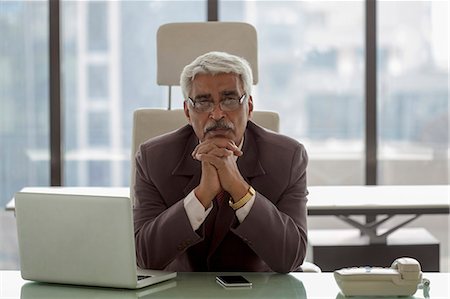 India, Portrait of senior businessman siting at desk with hands under chin Photographie de stock - Premium Libres de Droits, Code: 655-08357155