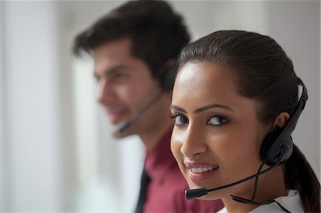 simsearch:6109-06002816,k - India, Young telemarketer looking at camera with her colleague in background Stock Photo - Premium Royalty-Free, Code: 655-08357172