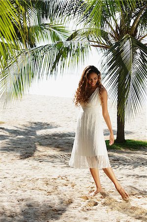 young woman walking in the sand with coconut trees in background Stock Photo - Premium Royalty-Free, Code: 655-03519635