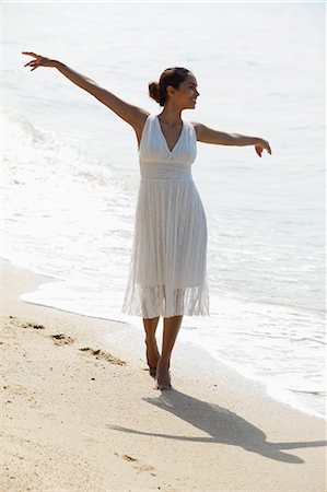 young woman with arms out stretched walking along the beach Stock Photo - Premium Royalty-Free, Code: 655-03519676