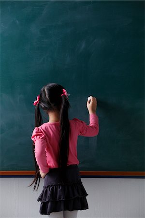 study - rear view of young girl with pony tails writing on chalkboard Stock Photo - Premium Royalty-Free, Code: 656-04926475