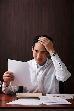 straining (overexertion) - man sitting at desk holding paper looking stressed Foto de stock - Sin royalties Premium, Código: 656-04926574