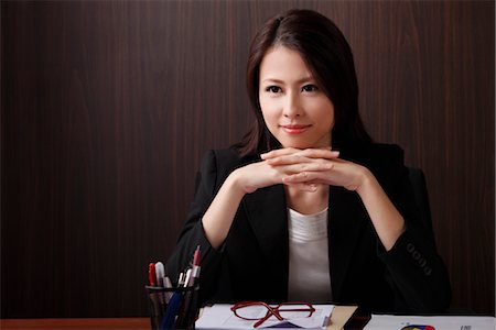 Woman sitting at desk with hands folded Stock Photo - Premium Royalty-Free, Code: 656-04926591