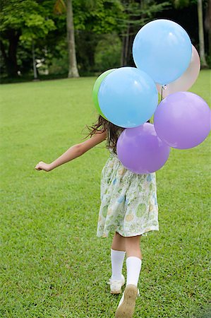 Girl walking on grass, holding balloons, rear view Stock Photo - Premium Royalty-Free, Code: 656-01765195