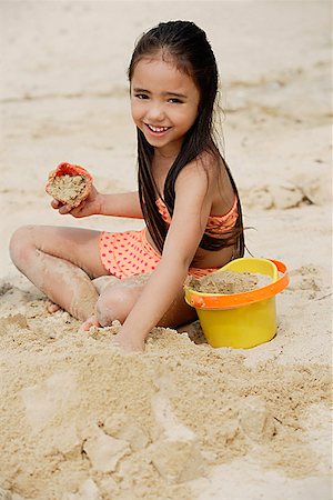 Young girl building sand castle on beach, smiling Stock Photo - Premium Royalty-Free, Code: 656-01765327