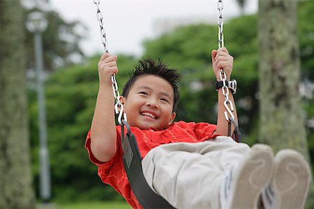 Boy on playground swing, smiling, looking away Stock Photo - Premium Royalty-Free, Code: 656-01765415