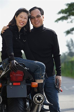 simsearch:841-02720357,k - Mature couple looking at camera, woman sitting on motorcycle Stock Photo - Premium Royalty-Free, Code: 656-01765428