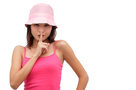 shhh - Young woman wearing pink hat with finger to mouth, be quiet please Stock Photo - Premium Royalty-Free, Code: 656-01765511