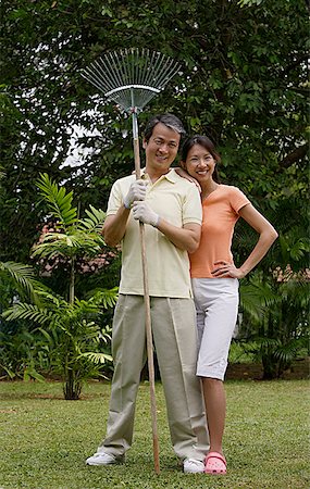 simsearch:841-02720357,k - Couple standing side by side in garden, man holding garden rake Stock Photo - Premium Royalty-Free, Code: 656-01765596