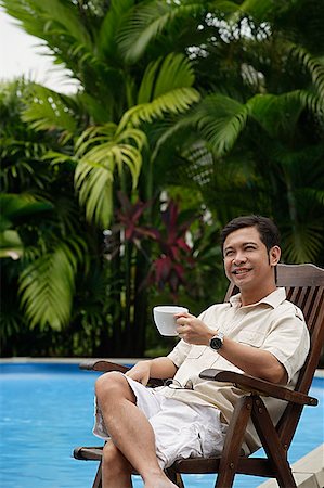 people relaxing in pool chairs - Man sitting by swimming pool, holding a cup of coffee, smiling Stock Photo - Premium Royalty-Free, Code: 656-01765839