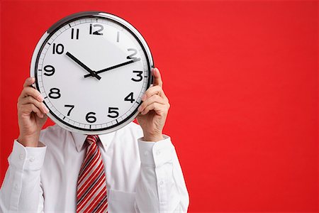 A man holds a clock in front of his face Stock Photo - Premium Royalty-Free, Code: 656-01766261